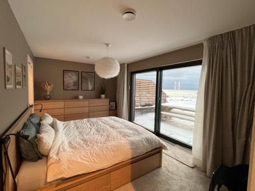 a bedroom with a bed and a large window at Bausje Beach House in Farsund