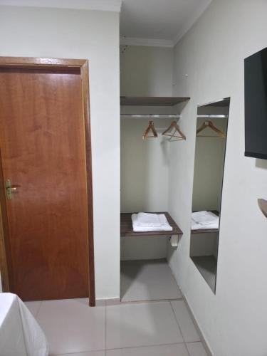 a bathroom with a wooden door and a mirror at Pousada Alvorada in Engenheiro Coelho
