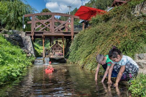 two children playing in the water in a river at Penzión Banská Klopačka in Hnilčík