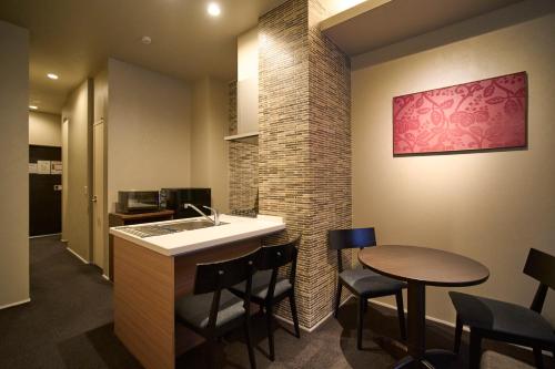 a kitchen with a sink and a bar with stools at Kyohotel Kishotei Goshominami in Kyoto