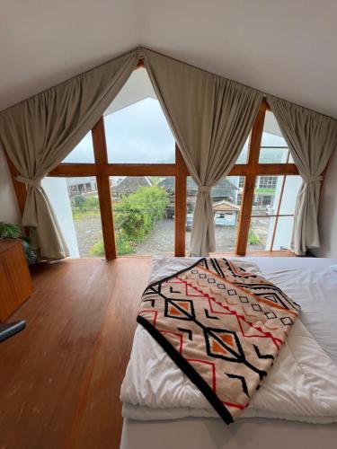 a bedroom with a bed with a large window at Cottage Linggayoni Dieng in Diyeng
