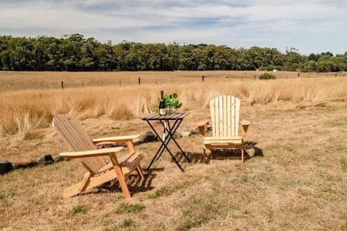 two chairs and a table with a bottle of wine at Tiny Divine Farmstay by Tiny Away in Korweinguboora