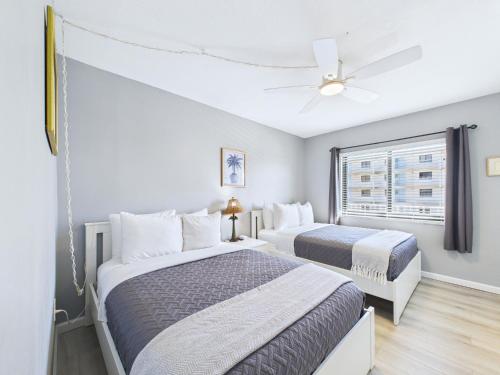 two beds in a bedroom with a ceiling fan at Sandcastles 2BR2BA Cocoa Beach Ocean Views! in Cocoa Beach