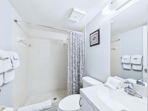 a white bathroom with a toilet and a shower at Sandcastles 2BR2BA Cocoa Beach Ocean Views! in Cocoa Beach