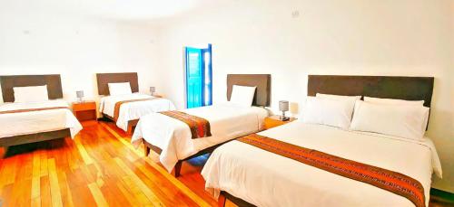 a hotel room with three beds in a room at Cusco - Flor de Loto in Cusco