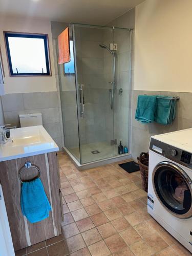 a bathroom with a shower and a washing machine at Matapouri Sanctuary Apartment in Matapouri