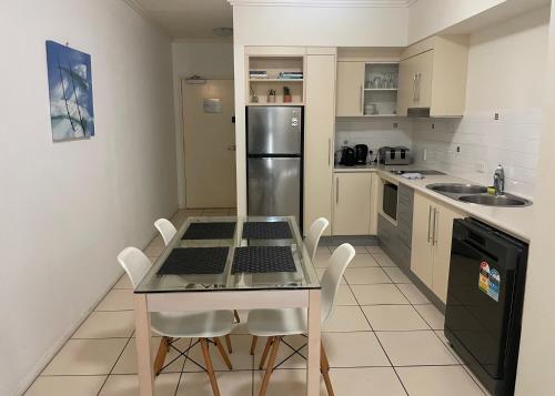 a kitchen with a table and chairs and a refrigerator at City Quays Private Apartments - Best CBD Location & Comfort in Cairns