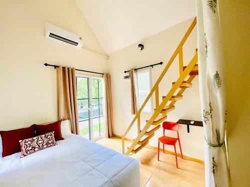 a bedroom with a bed and a staircase and a chair at Tiny Secret in Ban Tai