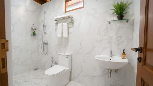 a white bathroom with a toilet and a sink at PULAU LIMA Resort in Serang