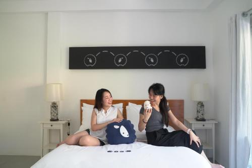 two women sitting on a bed looking at each other at Kokotel Khao Lak Isara Casa in Khao Lak