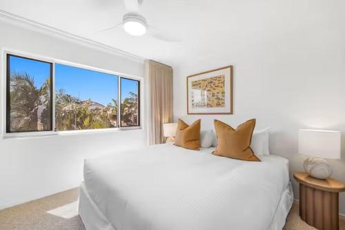 a white bedroom with a large bed and a window at Joanne Apartments in Caloundra