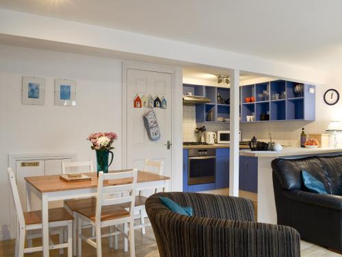 a kitchen and living room with a table and chairs at Windjammer Cottage in Swanage