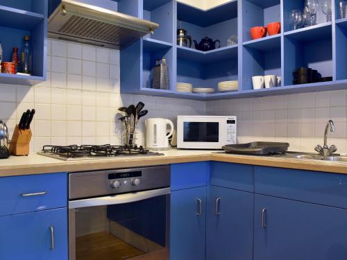 a blue kitchen with a stove and a microwave at Windjammer Cottage in Swanage