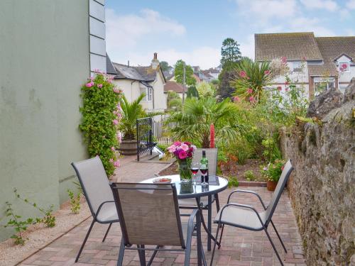 a patio with a table and chairs and flowers at Samphire Lodge in Brixham
