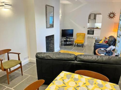 a living room with a black leather couch and chairs at Samphire Lodge in Brixham