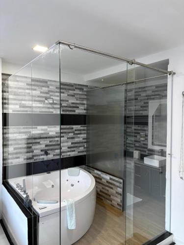a bathroom with a tub and a glass shower at Hotel Blue Paradise inn in Turbo