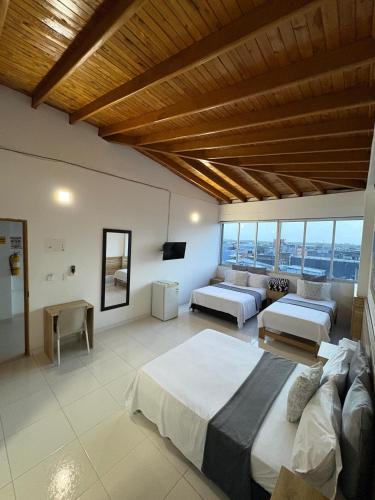 a large bedroom with two beds and a large window at Hotel Blue Paradise inn in Turbo