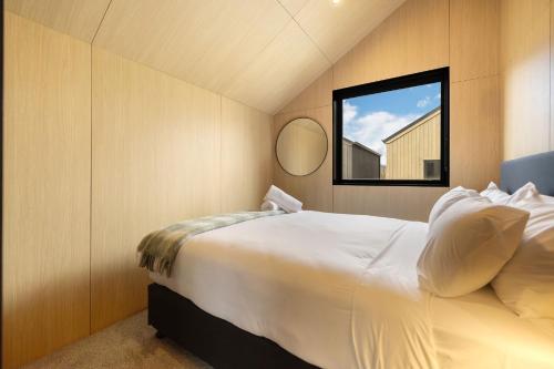 a bedroom with a large white bed and a window at Rere Villa Queenstown in Queenstown