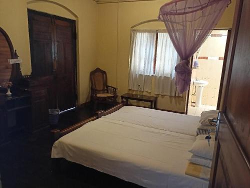 a bedroom with a large bed and a window at Olde Empire Hotel in Kandy