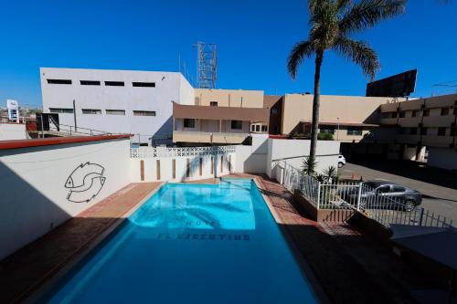 a swimming pool in front of a building with a palm tree at Hotel El Ejecutivo Tijuana in Tijuana