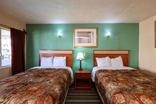 two beds in a hotel room with green walls at Hotel El Ejecutivo Tijuana in Tijuana