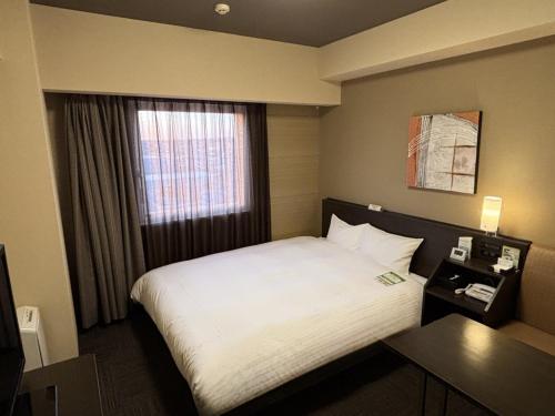 a hotel room with a bed and a window at Hotel Route Inn Hamamatsu Dealer Dori in Hamamatsu