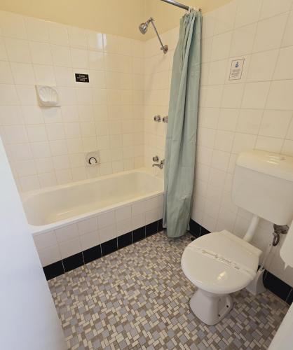 a bathroom with a toilet and a bath tub at Lakes Entrance RSL Glenara Motel in Lakes Entrance