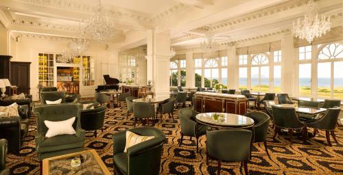een grote kamer met stoelen, tafels en ramen bij Trump Turnberry in Turnberry