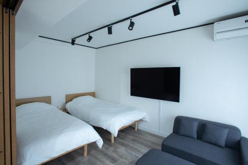 a bedroom with two beds and a chair and a tv at LUCKY house53 in Tokyo