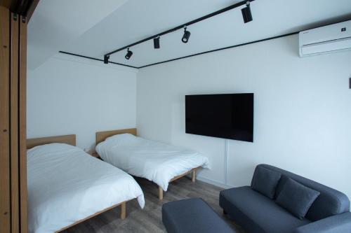 a room with two beds and a tv and a couch at LUCKY house53 in Tokyo