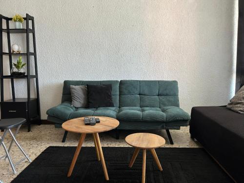 a living room with a green couch and two tables at Comfortable apartment 10 min BBVA Stadium - Wi-fi Parking SmartTV & AC in Monterrey