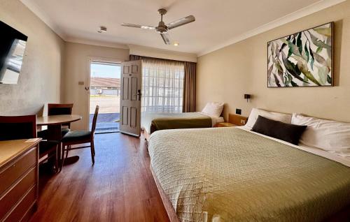 a hotel room with a bed and a desk and a table at Colonial Terrace Motor Inn in Raymond Terrace