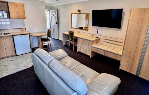 a living room with a couch and a flat screen tv at Colonial Terrace Motor Inn in Raymond Terrace