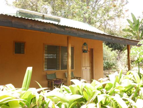 a small orange house with a chair in front of it at Meru Mbega Lodge in Usa River