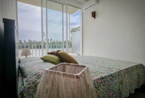 a bedroom with a bed and a large window at blu River villa Ambalangoda in Nikawatawana