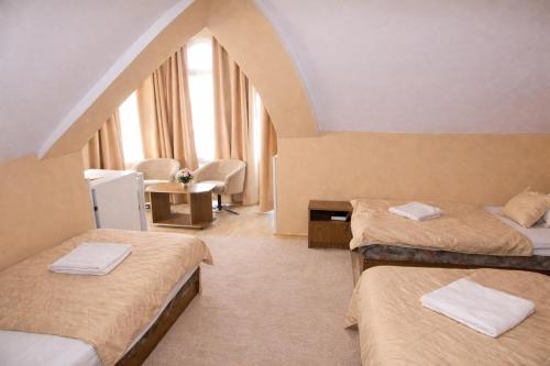 a room with two beds and a table with a chair at Lagúna Panzio Szántód in Szántód
