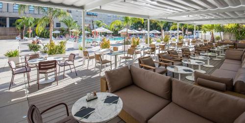 um restaurante com sofás e mesas e uma piscina em Melia Lebreros em Sevilha