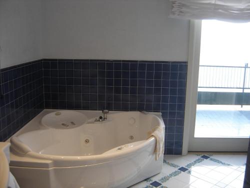 a bath tub in a bathroom with blue tiles at Hotel Continental in Sorrento