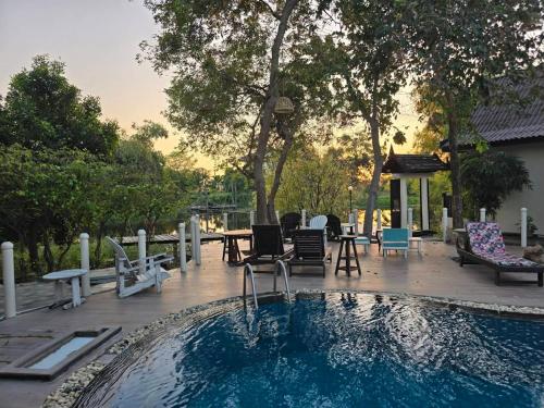 a swimming pool with chairs and a table and a patio at Pludhaya Resort & Spa in Phra Nakhon Si Ayutthaya
