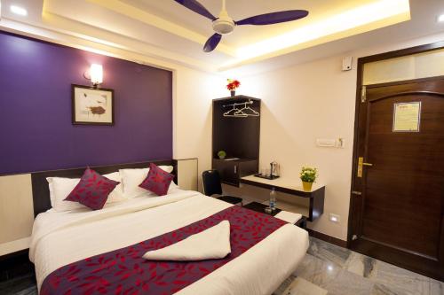 a bedroom with a bed and a desk and a door at Hotel Lotus in Madurai