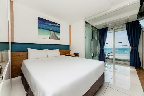 a bedroom with a bed and a view of the ocean at Hamdeok Beach Stay Jeju in Jeju