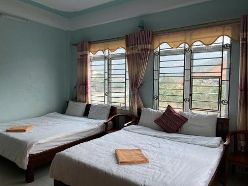 two beds in a room with two windows at Sunshine Loop Hostel in Làng Lap