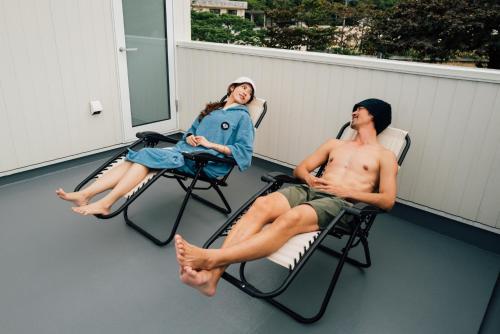 two people sitting in lawn chairs on a porch at Villala Fibana in Motobu