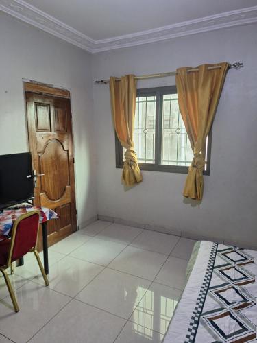 ein Zimmer mit einem Bett, einem Fenster und einem Schreibtisch in der Unterkunft Affiba Colocation in Abidjan