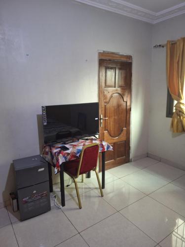 ein Zimmer mit einem Tisch, einer Tür und einem Stuhl in der Unterkunft Affiba Colocation in Abidjan