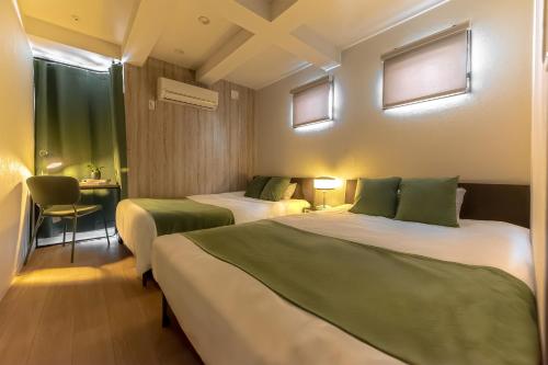 a hotel room with two beds and a table with a chair at 15 min Shinjuku ! Kitchen,Laundry! Perfect for a Long Stay I many facilities nearby I Shinjuku,Tokyo in Tokyo
