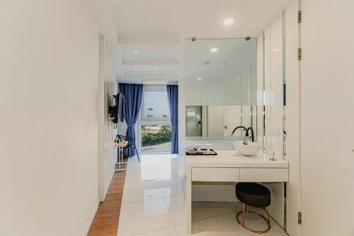 a white bathroom with a sink and a mirror at Hamdeok Beach Stay Jeju in Jeju