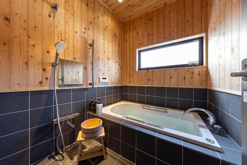 a bathroom with a tub in a wooden wall at こんぴら町家 Konpira Machiya in Kotohira