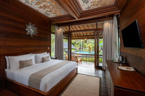 a bedroom with a bed and a tv and a balcony at Emana Abian Taksu in Ubud