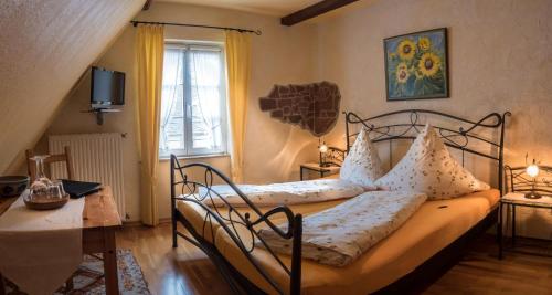 a bedroom with a bed and a table and a window at Weingut Herrenhof Andrea Thielen in Minheim